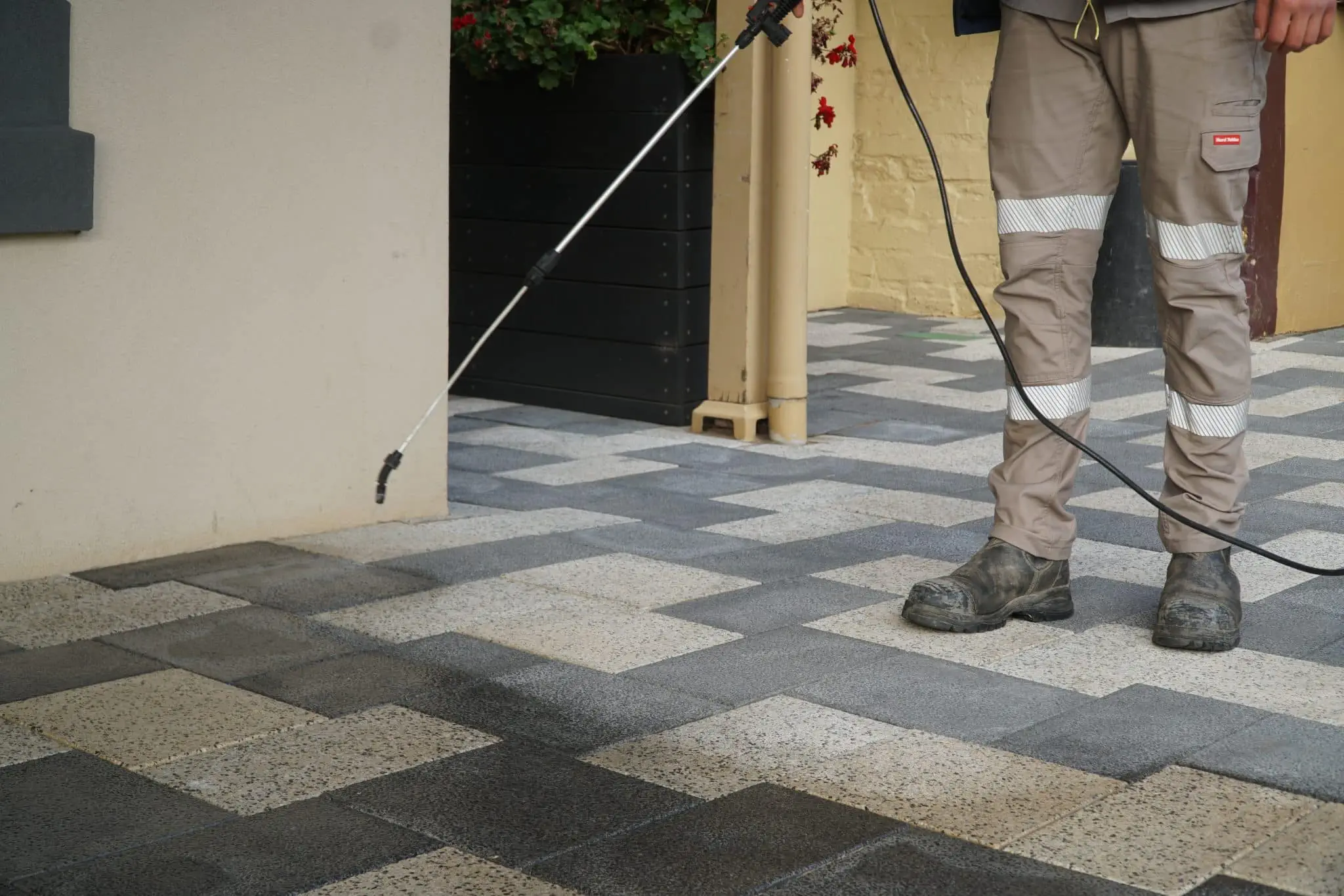 Worker applying hard surface sealing on the outdoor tiled area