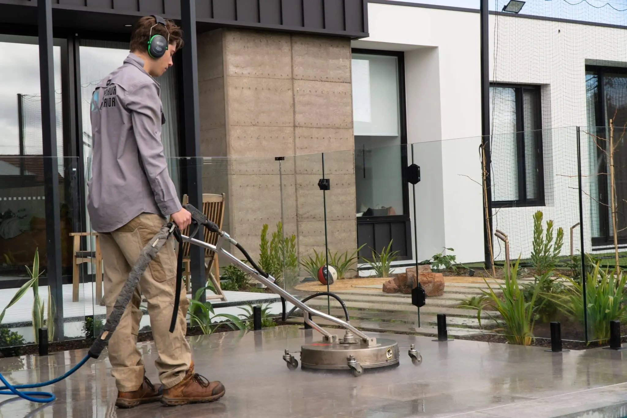 Professional Concrete Cleaners using pressure washers on a modern patio