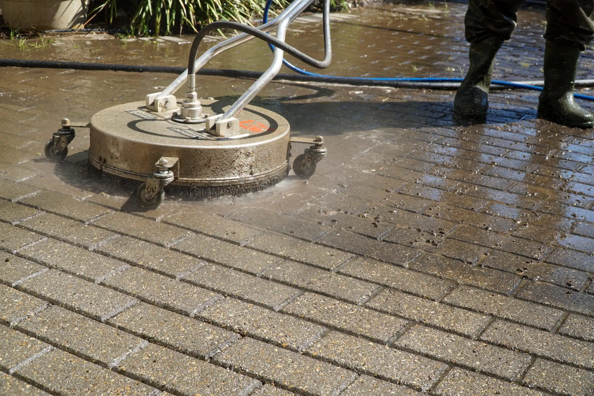 Close-up of a pressure washer cleaning a brick patio surface