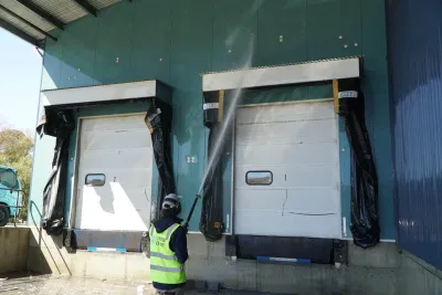 Professional cleaning service using a high-pressure washer to remove bird droppings from an industrial loading dock